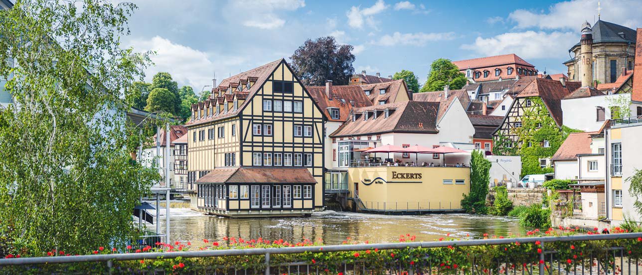 Blick von der Bischofsmühlbrücke in Bamberg auf den Eckerts Biergarten an einem sonnigen Frühlingstag