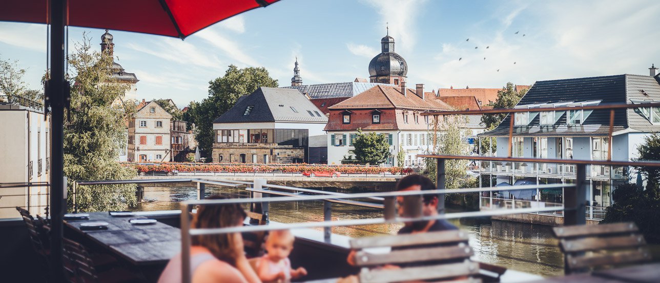 Von der Dachterrasse des Restaurant Eckerts schweift der Blick über den Fluss und das Bamberger Brückenrathaus